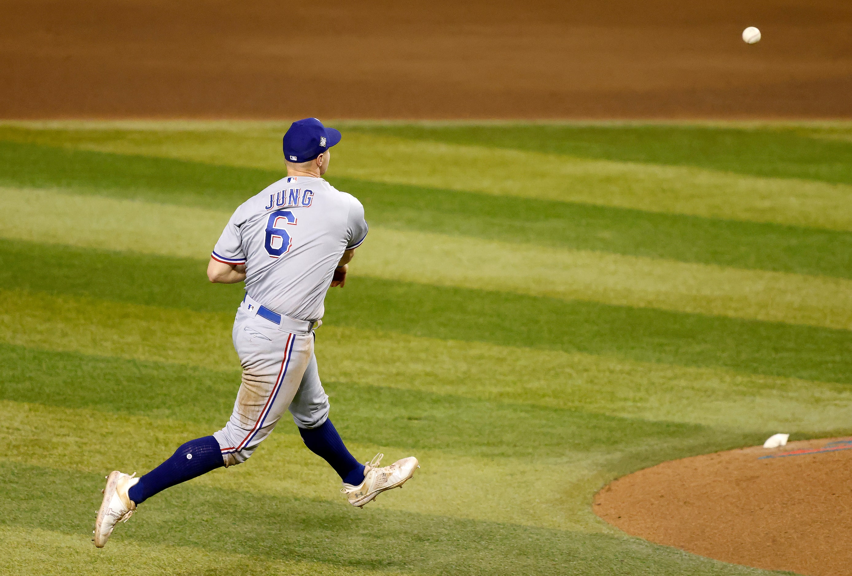 Texas Rangers third baseman Josh Jung charges an infield hit and attempts to throw out...