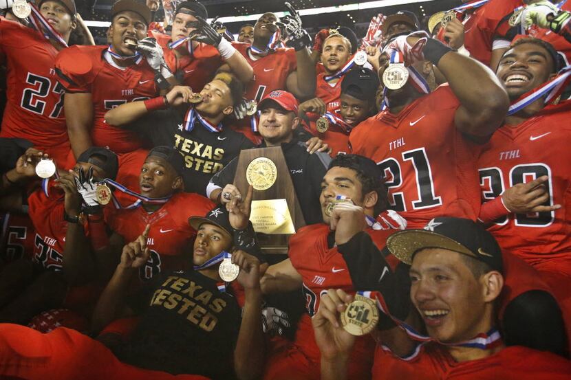 Cedar Hill head coach Joey McGuire is surrounded by his players as they pose with the trophy...