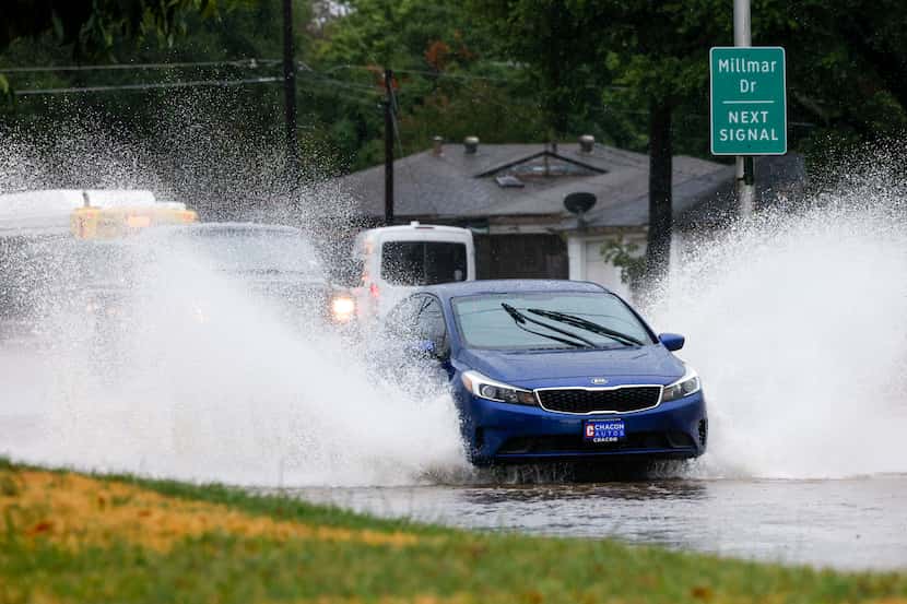 Cars drive through high flood waters along Ferguson Road near Millmar Drive in Dallas,...