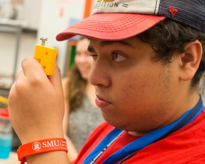 Joshua Reveles, 17, of Dallas, eyes up a hinge fitting for his team's project during an...