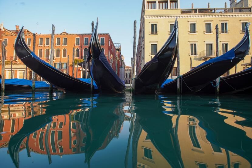 Moored gondolas are reflected on the water of the Gran Canal in Venice, during stay-at-home...