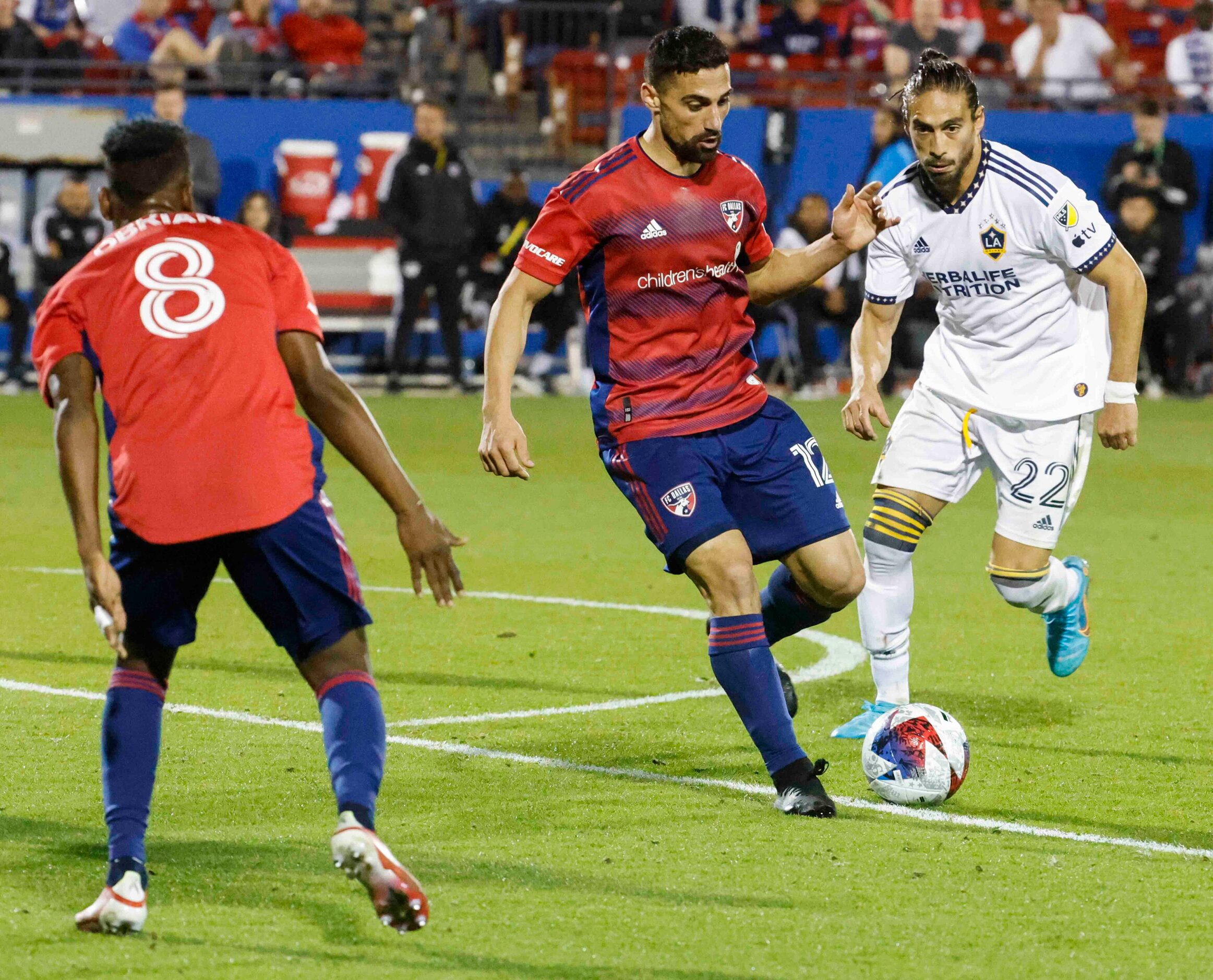 FC Dallas midfielder Sebastian Lletget (center) passes the ball past Los Angeles Galaxy...