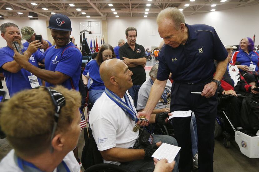 Roger Staubach, right, looks over the medals won by Bobby Click, center, of Ashland, Ohio, ...
