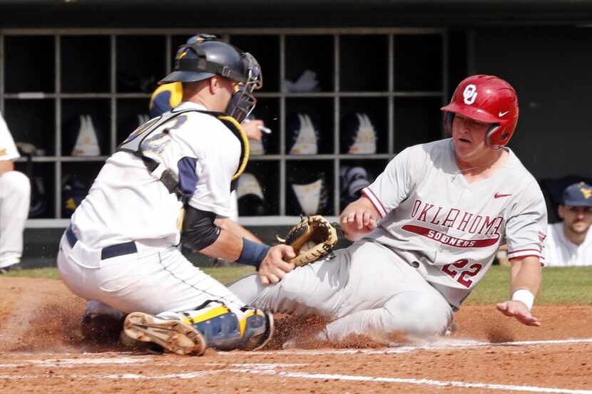 Oklahoma's Sheldon Neuse, right, is tagged out at home by West Virginia's Ray Guerinni in...