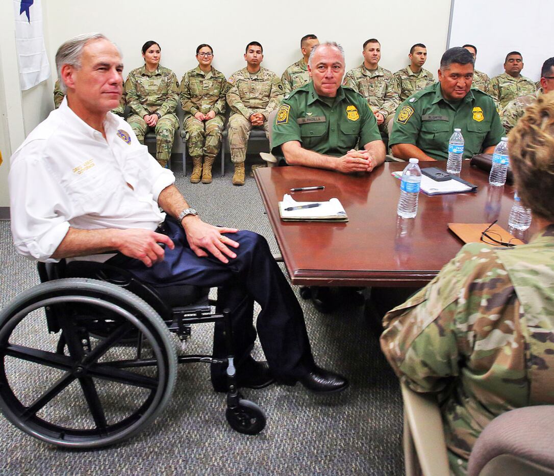 Texas Gov. Greg Abbott, left, talks with leaders of the Texas National Guard and the U.S....
