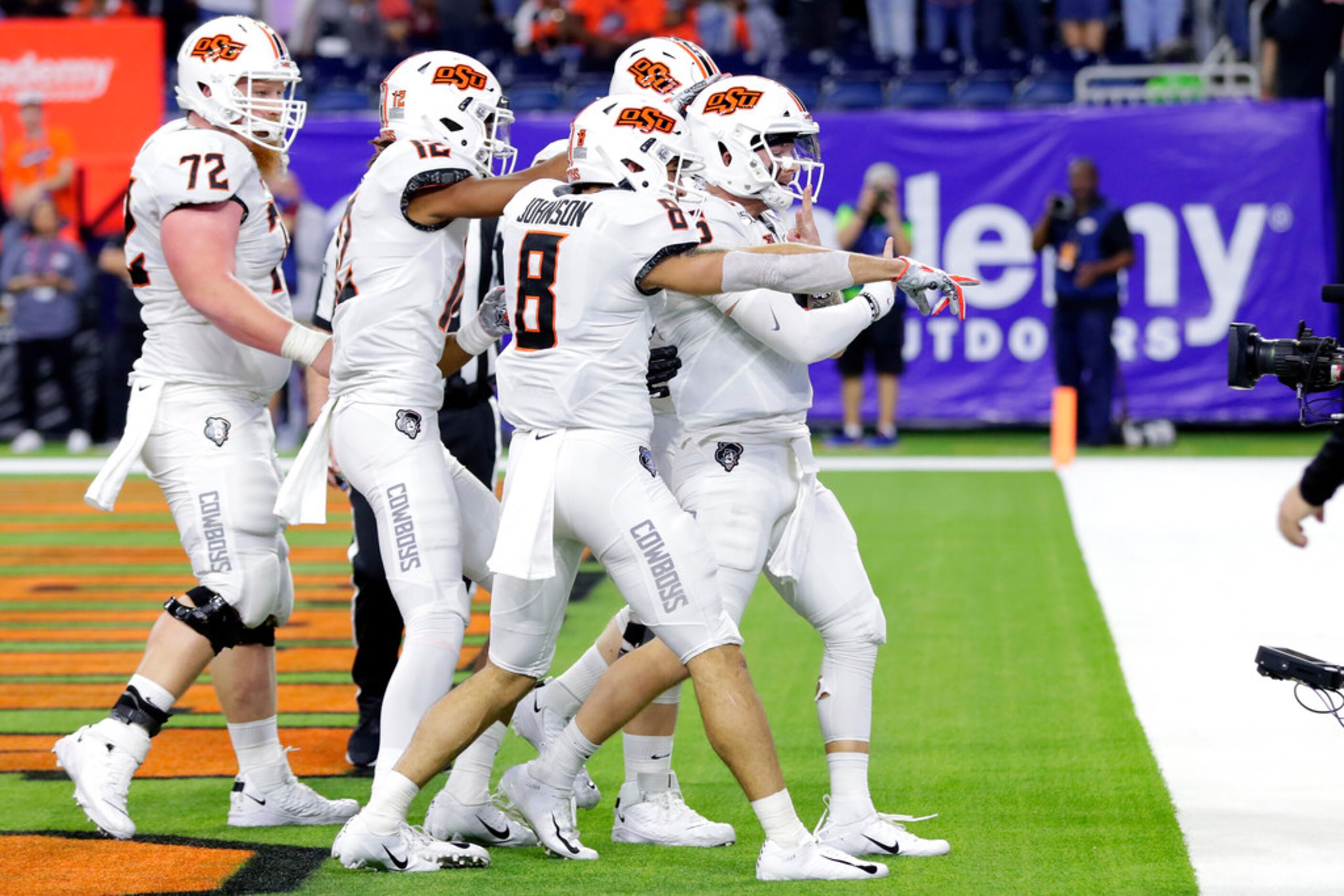 Oklahoma State players, led by quarterback Dru Brown, front, point at end zone camera as...