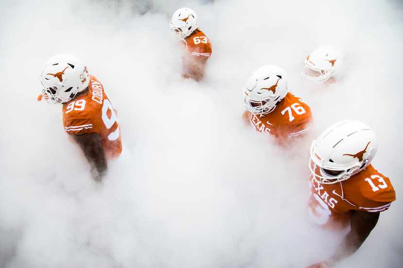 Texas Longhorns walk through smoke to enter the stadium before a college football game...