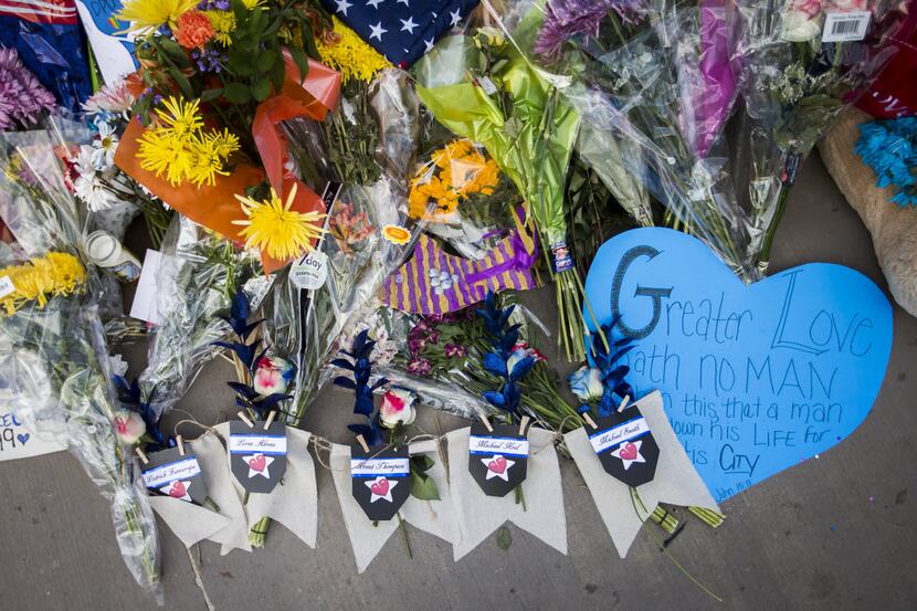 Flowers bearing the names of five fallen peace officers rest with other messages of support...