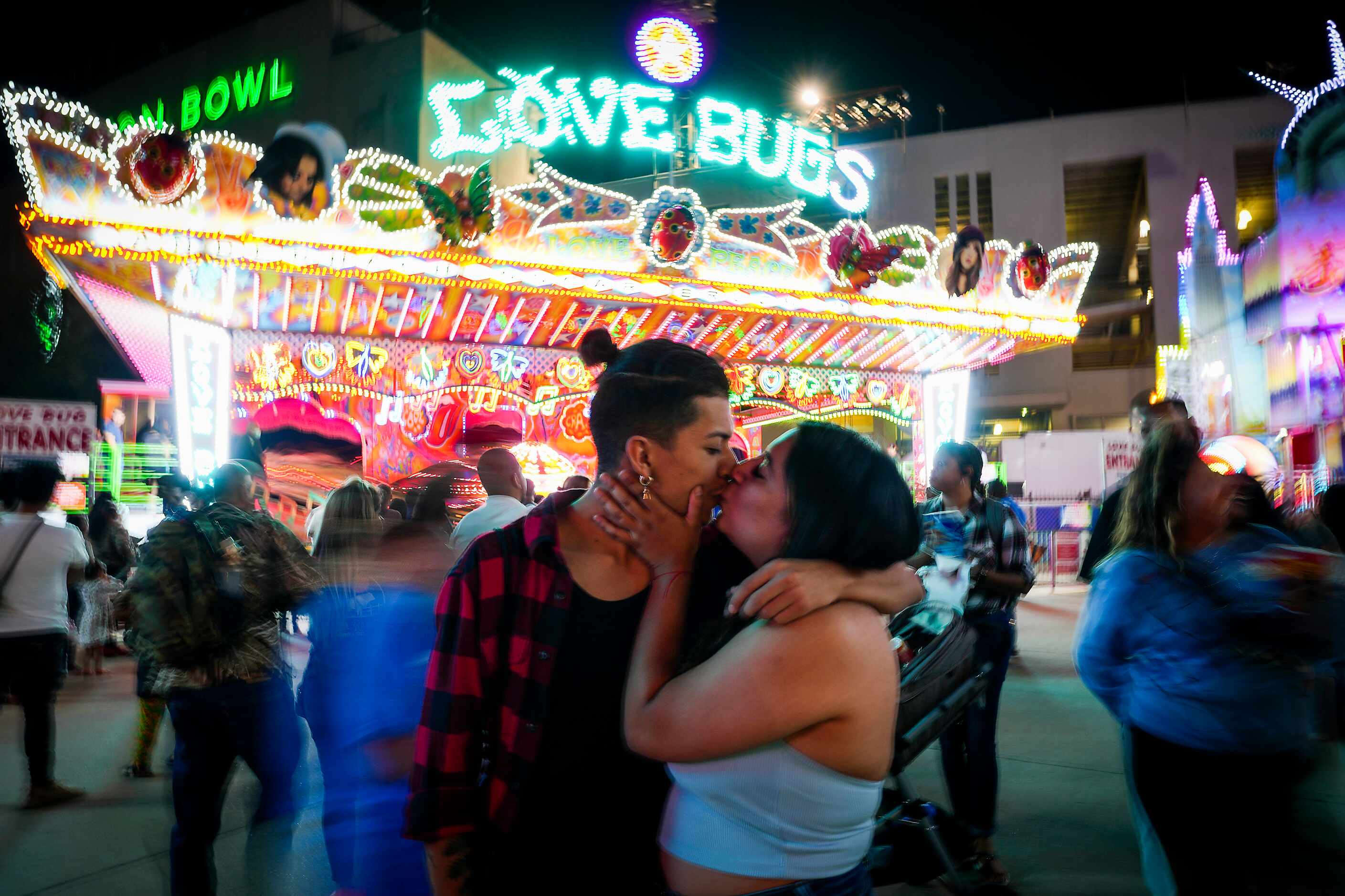 Sergio Pina kisses Jamie Pardo in front of the appropriately named Love Bugs ride on the...