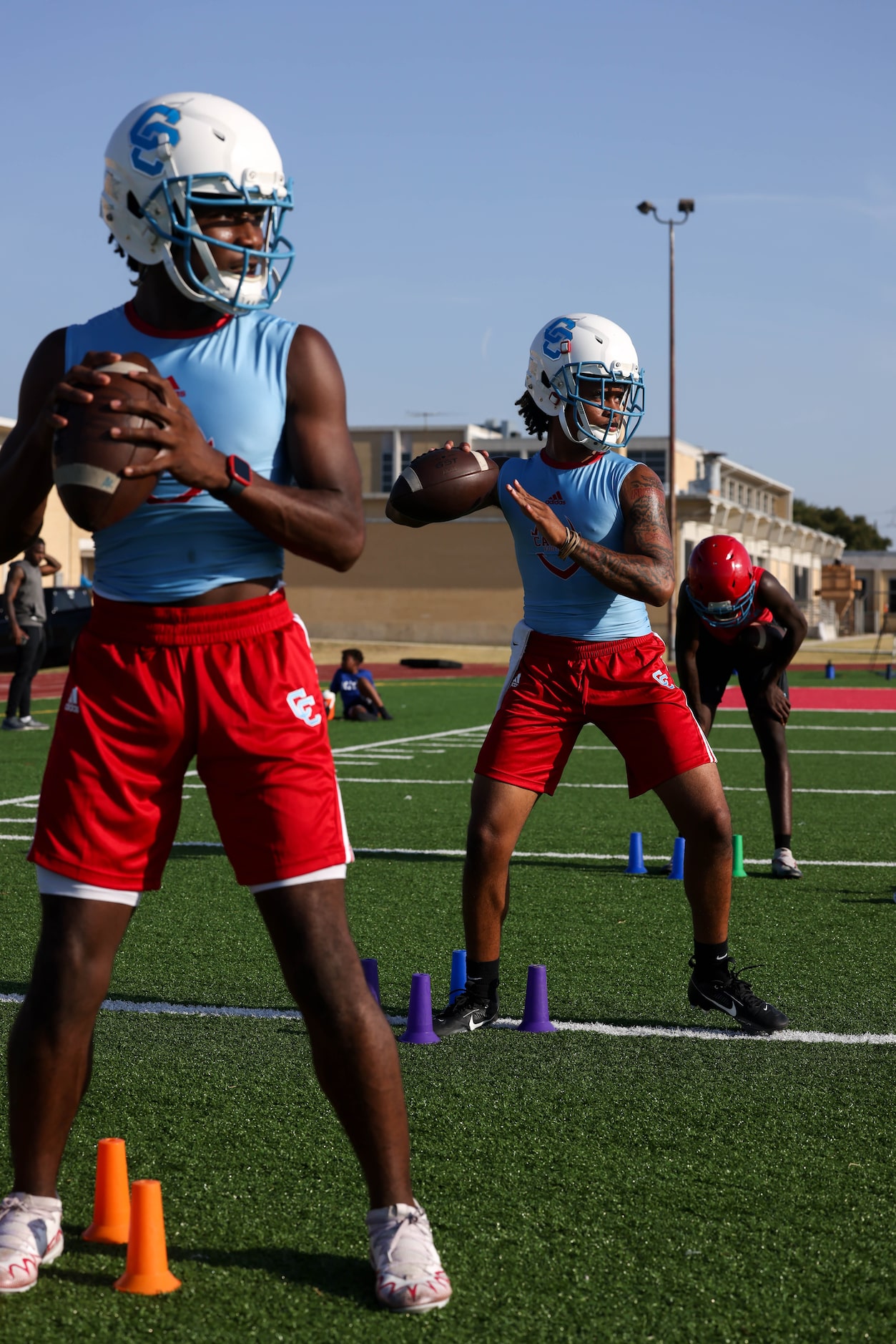 Quarterbacks Caleb Richardson (left) and Quay Robinson (center) line up for a throwing drill...