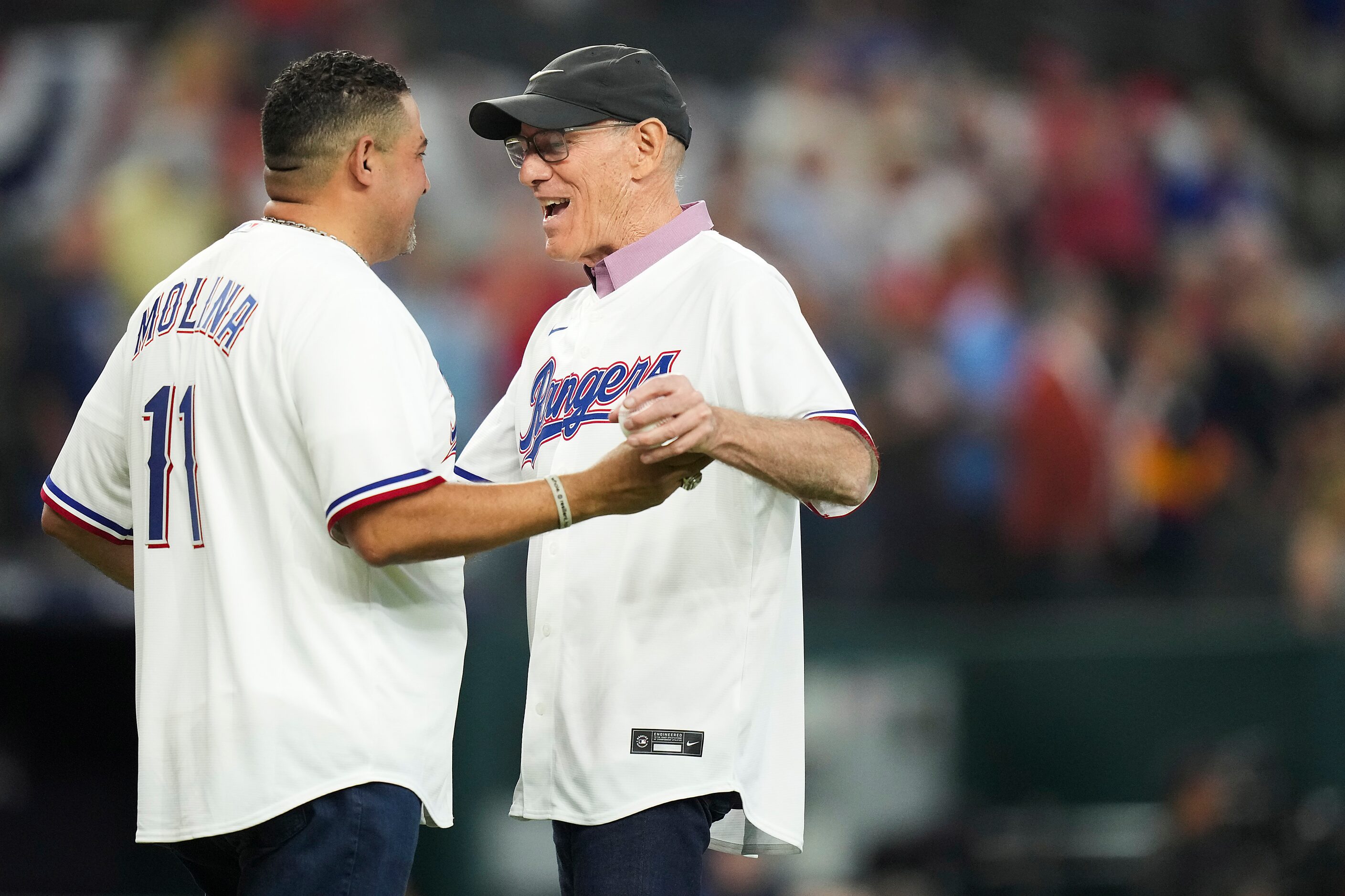 Rangers Hall of Famer Tom Grieve hugs former Rangers catcher Bengie Molina after throwing...