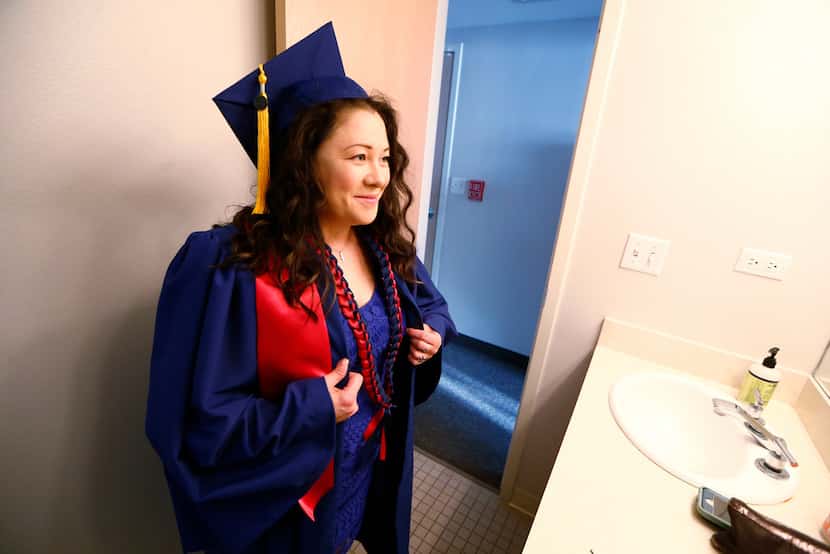 Wendy Birdsall looks at herself in the mirror after putting on her cap and gown before...
