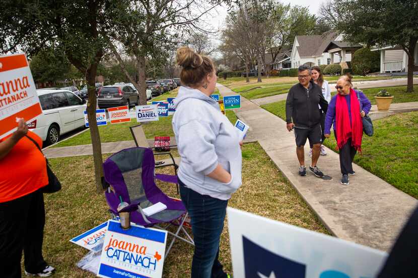 A group of voters pass by campaign volunteers while on their way to vote in the primary...