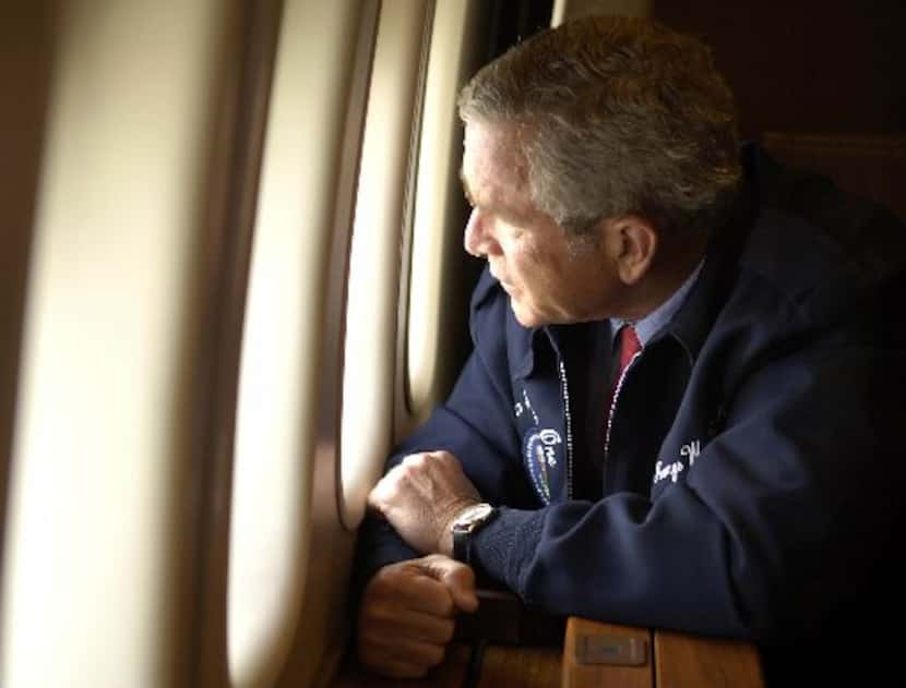 President George W. Bush peers out the cabin window of  Air Force One as he surveys the...