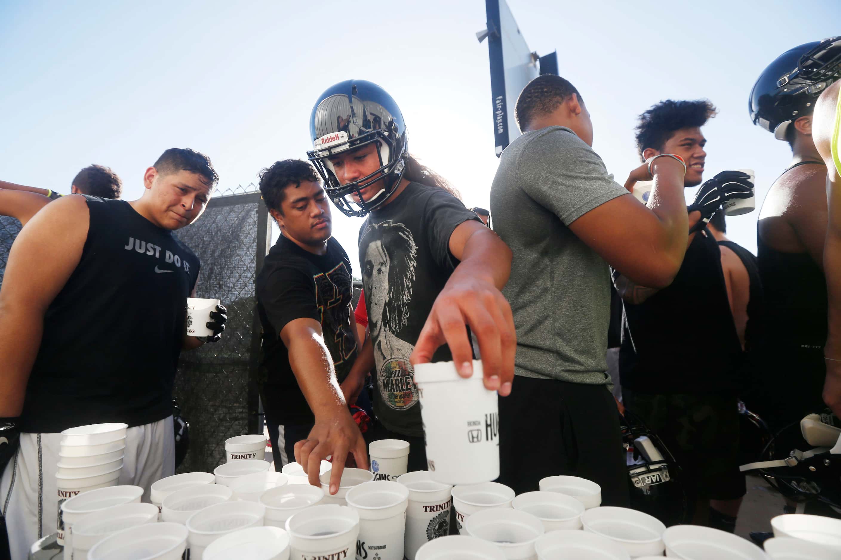 Jeremiah Kneubuhl, center, grabs a gatorade with teammates during Euless Trinity's first day...