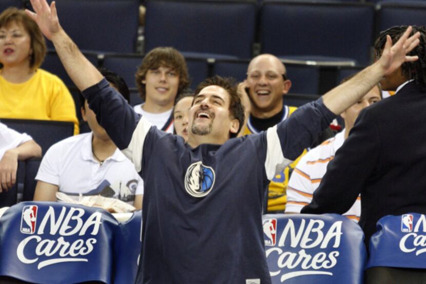 Dallas owner Mark Cuban laughs after making a shot from his seat in pre-game hijinx against...