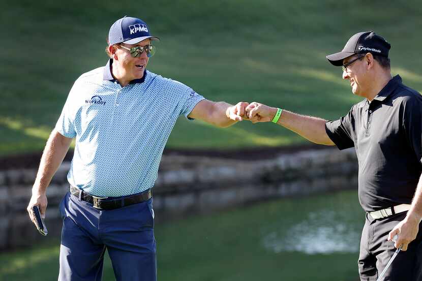 Golfer Phil Mickelson (left) gives a fist bump to playing partner Edgar Guevara after his...