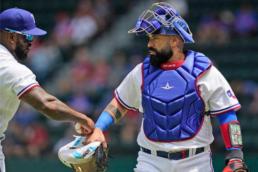 Texas Rangers catcher Sandy Leon, right, right walks on the field before a baseball game...