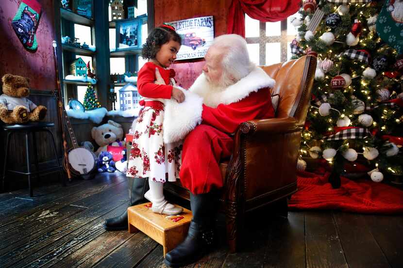 Santa Claus listens to 3 yr-old Abigail Campos of Richardson as she makes a visit to his...