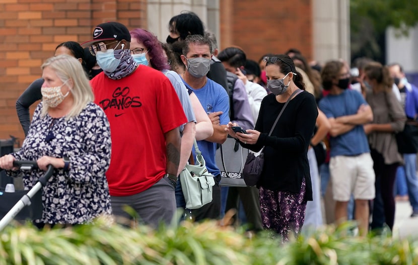 Voters wait to cast ballots at the American Airlines Center during early voting Thursday,...