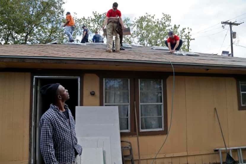 
Timothy Willis watched volunteers as they worked to replace the roof on his home Saturday...