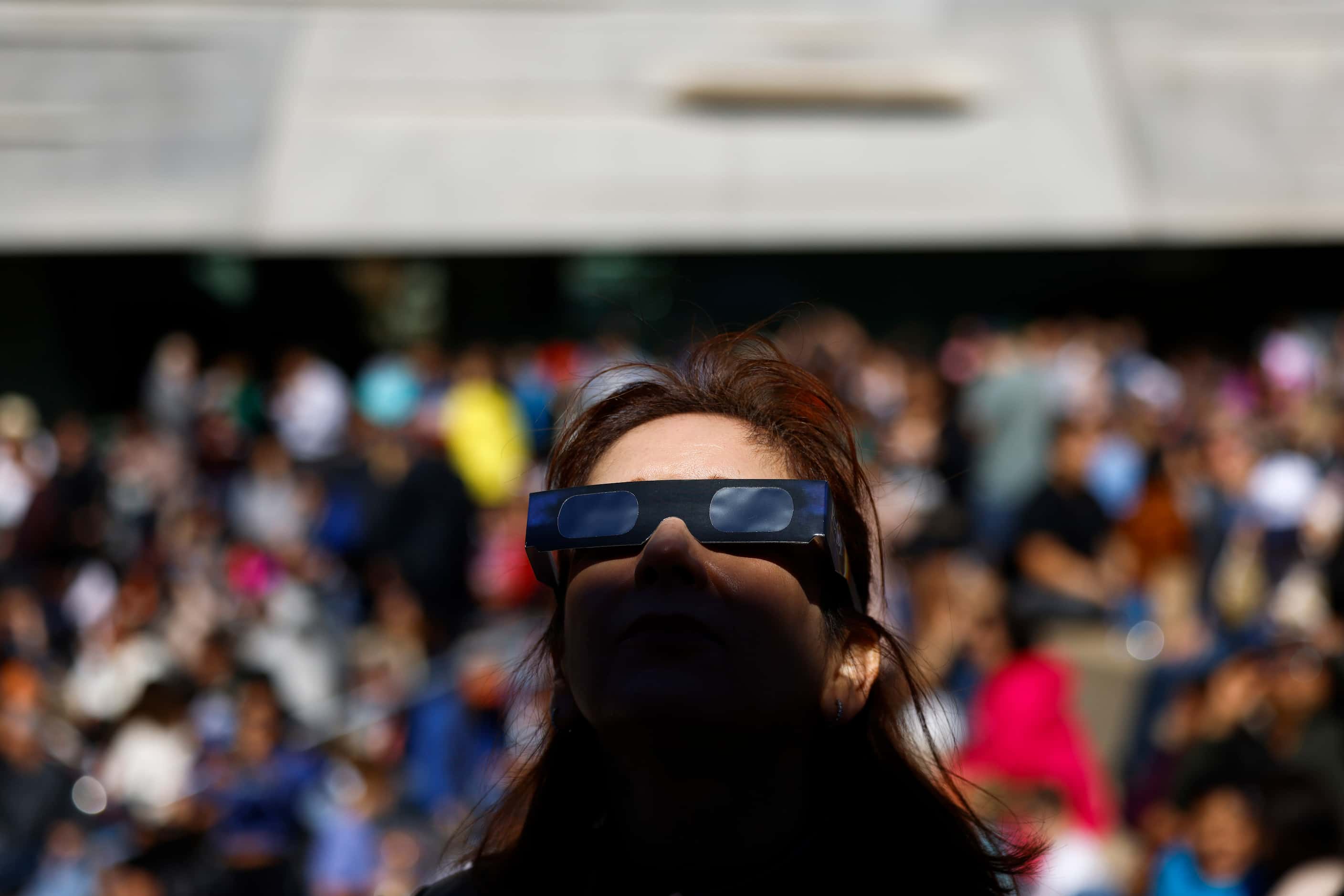A shadow casts on the face of Midia Camacho as she watches the annular solar eclipse on...