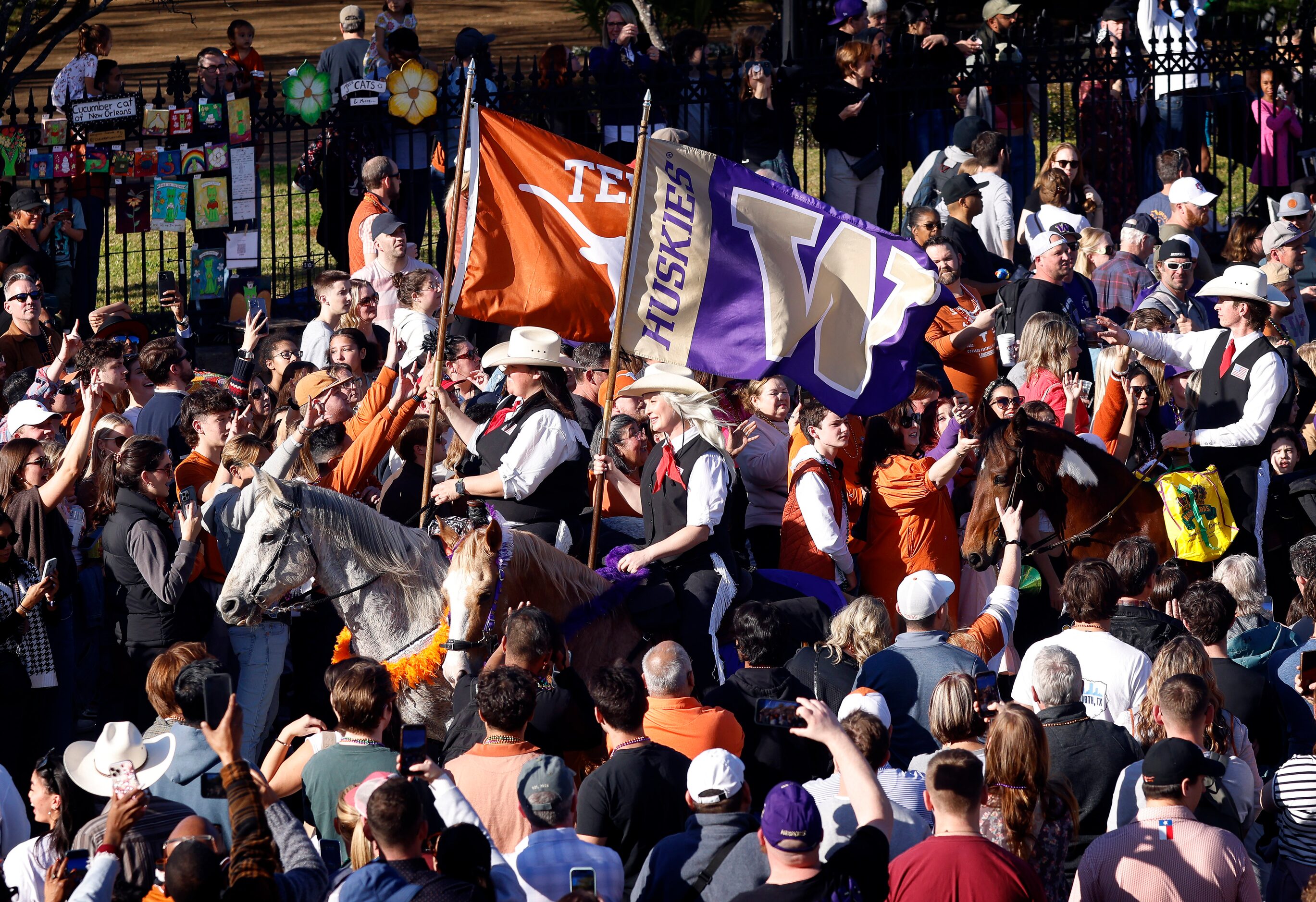 Members of the Urban Cowboys Riding Club carry the school flags of Texas and Washington...