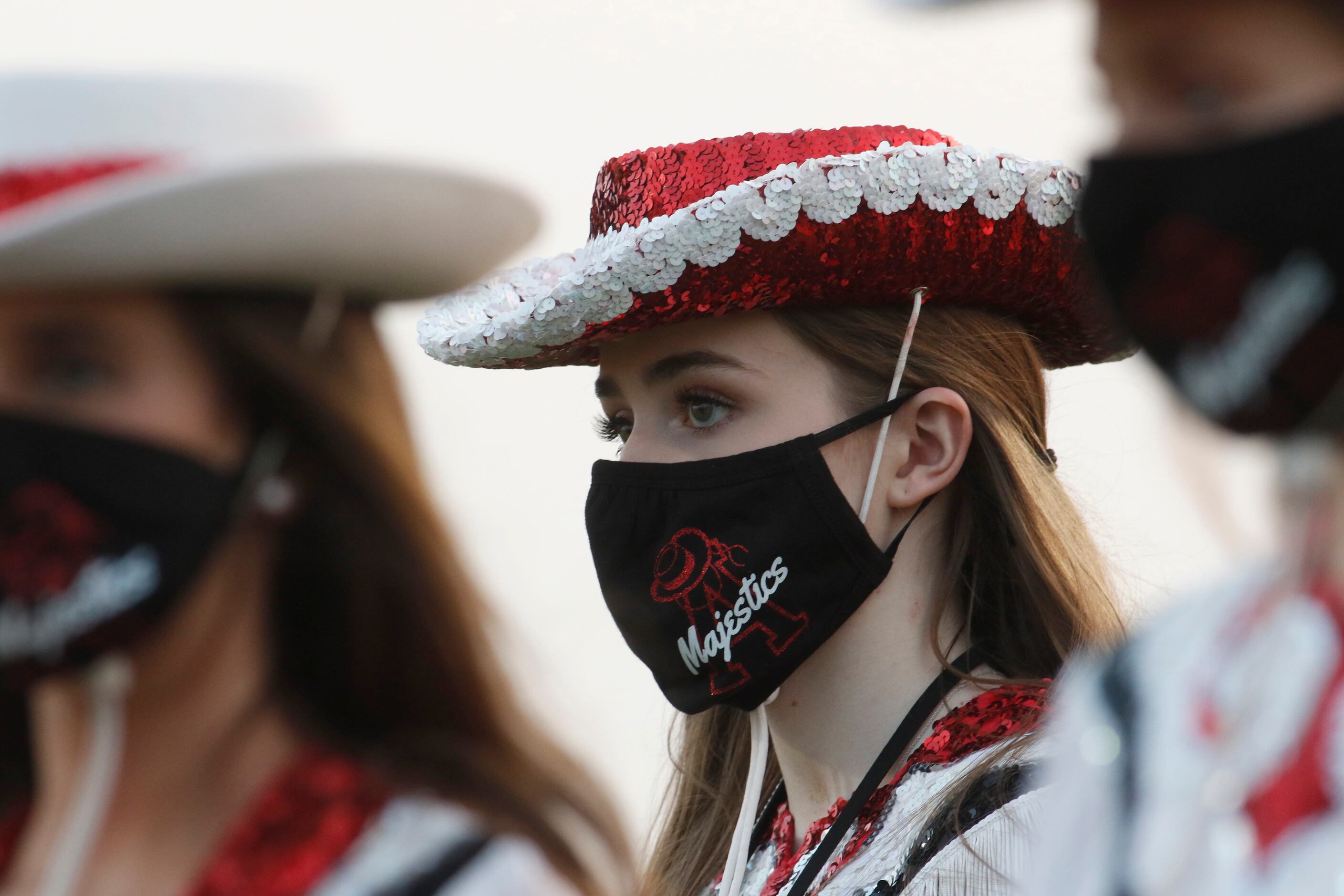 Members of the Argyle drill team don face coverings as they await their field performance...