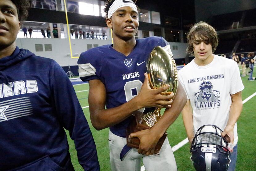 Frisco Lone Star High School defensive back Julian Larry (9) walks with the semifinal trophy...
