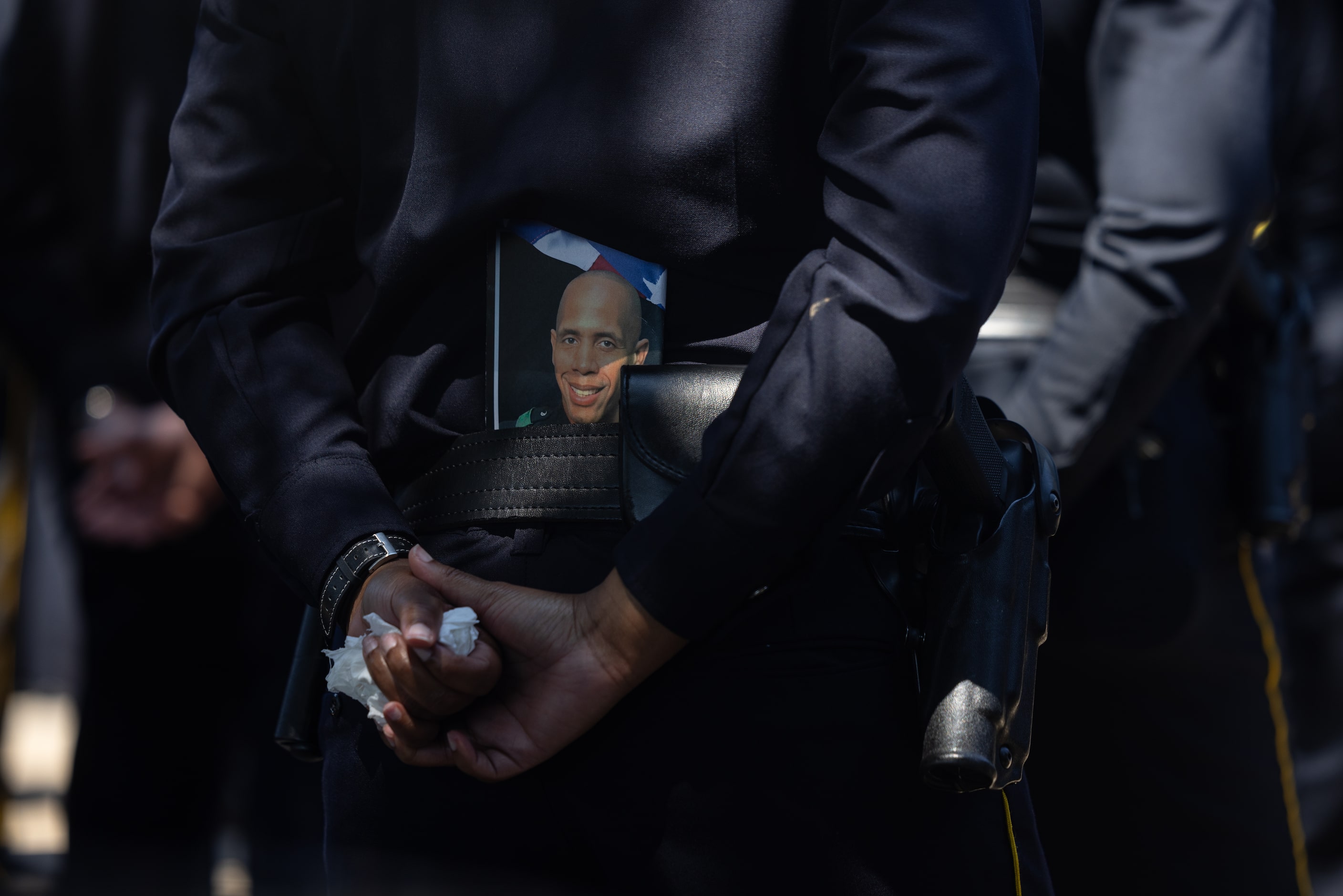 Officers stand with funeral programs tucked into their belts sat the funeral service of...