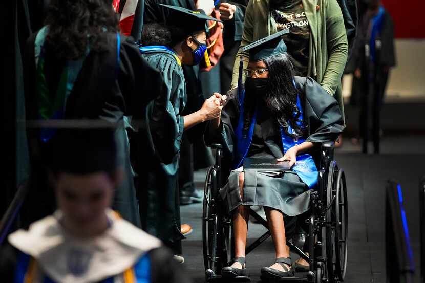 Eryn Fayson crosses the stage in a wheelchair to receive her diploma during commencement...