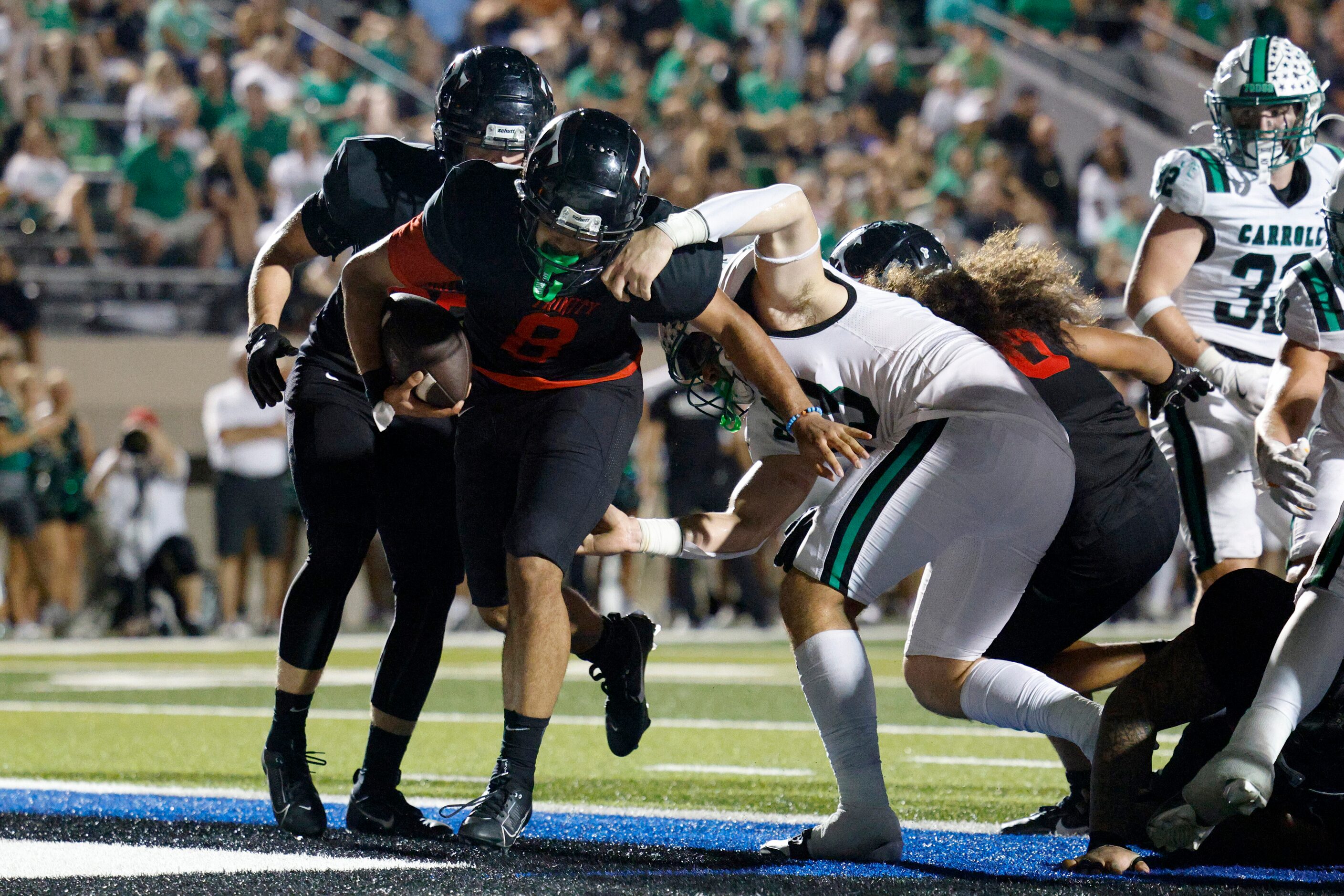 Euless Trinity quarterback TJ Tupou (8) rushes for a touchdown past Southlake Carroll...