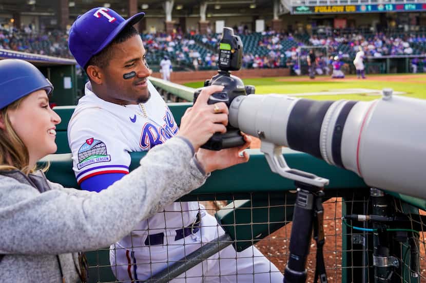 Texas Rangers infielder Andy Ibanez reviews photos of his 3-run home run on the back of the...