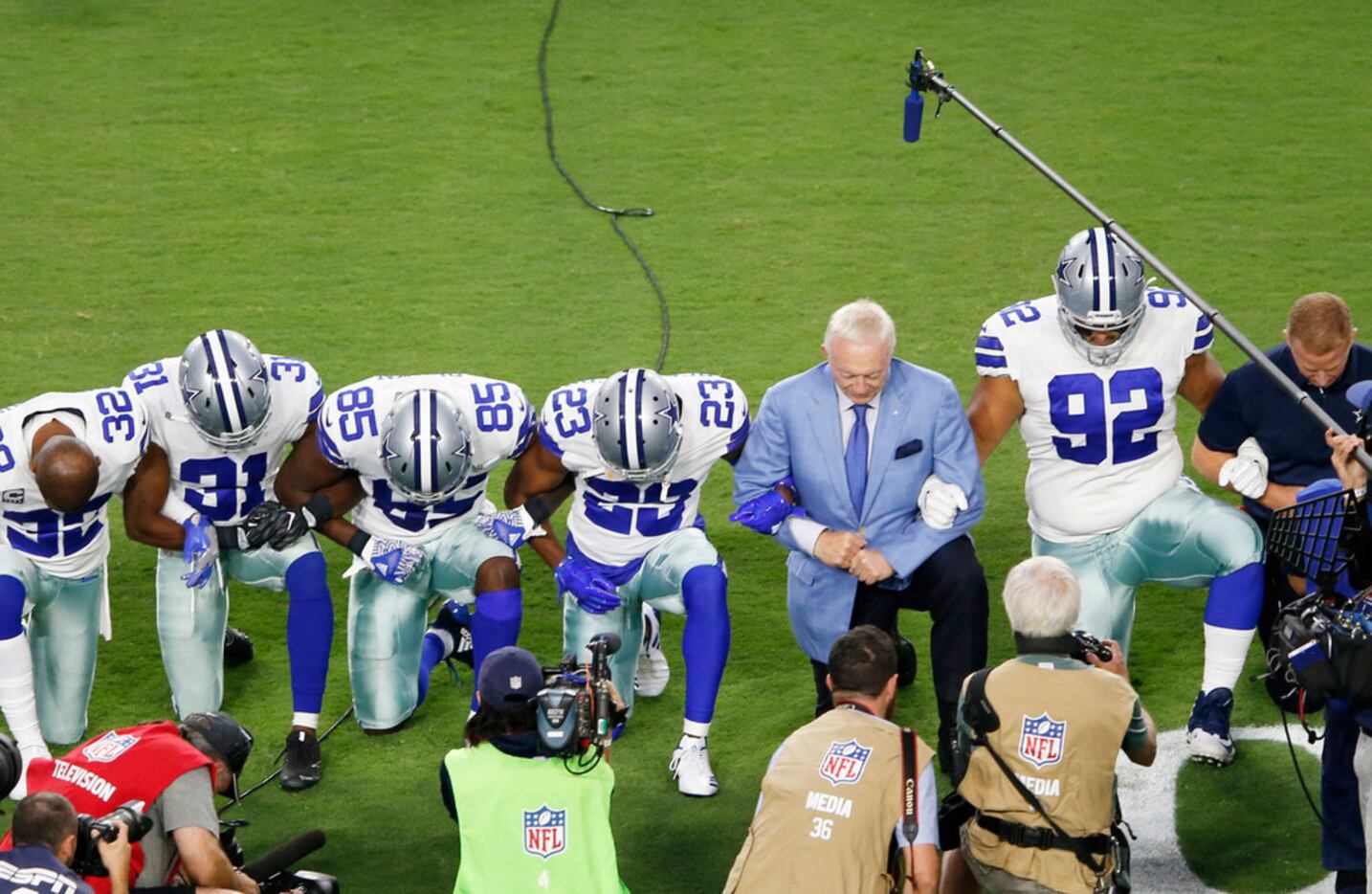 Dallas Cowboys owner and general manager Jerry Jones and team take a knee before the singing...