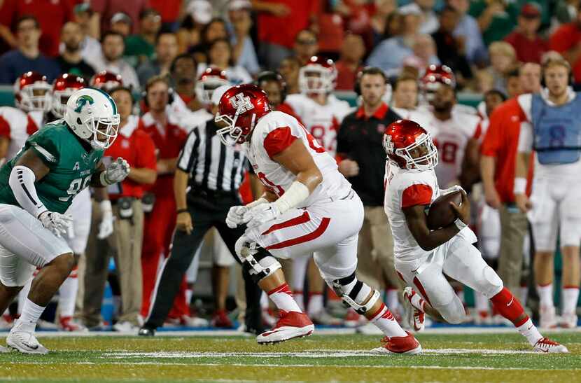 Houston quarterback Greg Ward Jr., right, runs out of the pocket under pressure from Tulane...