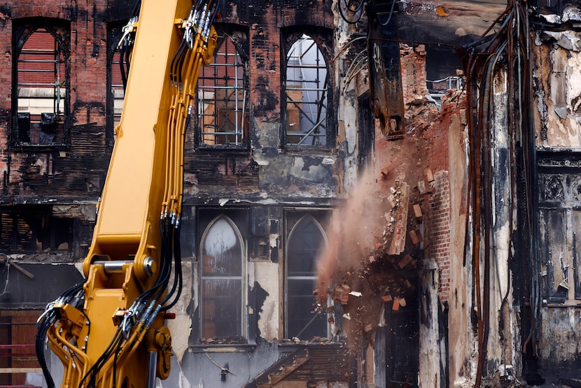 Demolition crews knock down a brick wall alongside the north wall (left) at the First...