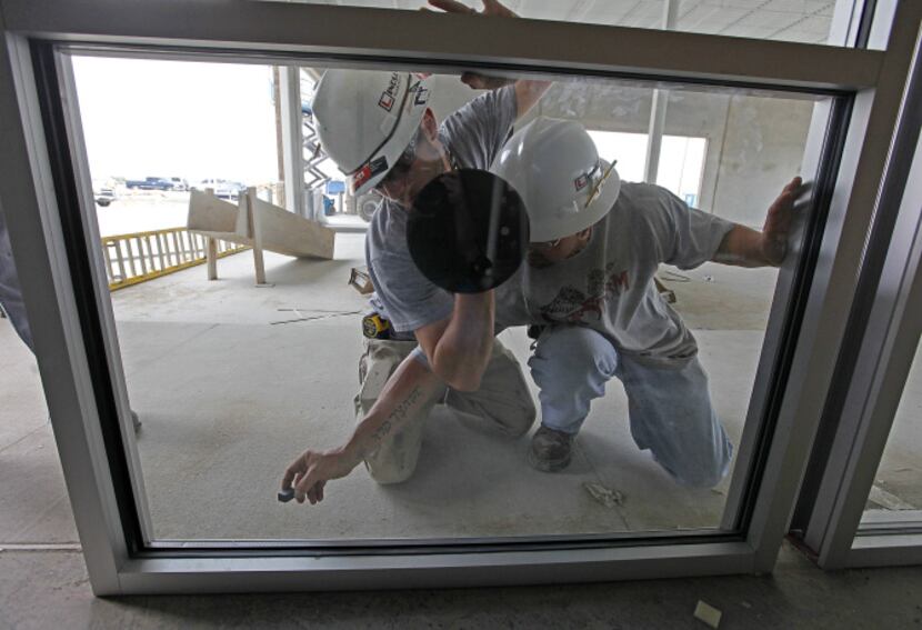 Lindsay Glass Systems workers install energy efficient panes that will help reduce the...