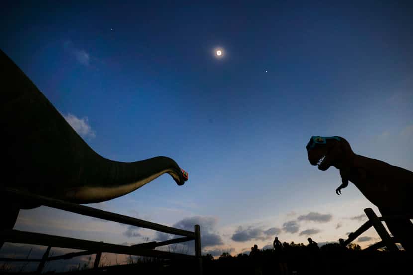 A total solar eclipse is seen above the dinosaur models at Dinosaur Valley State Park,...