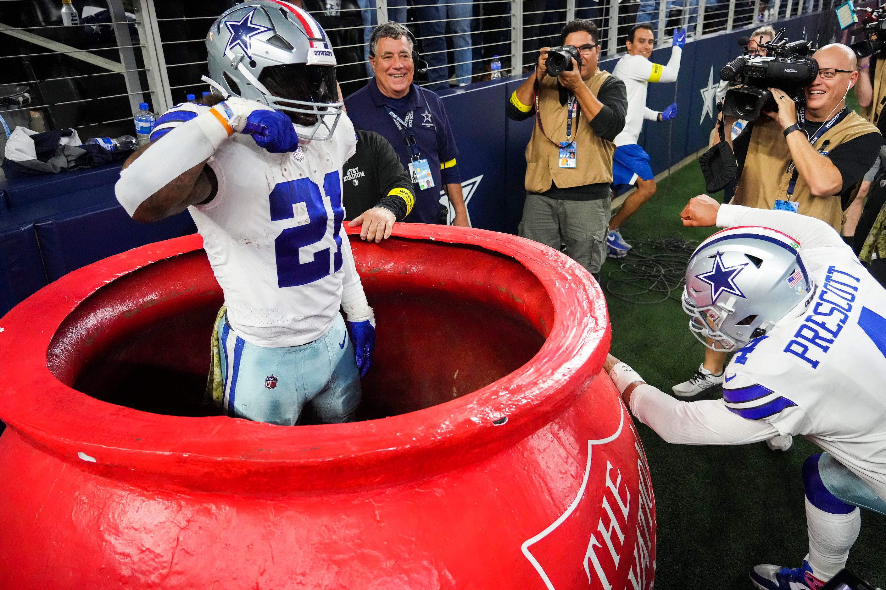 Dallas Cowboys running back Ezekiel Elliott (21) pops out of a Salvation Army kettle as...