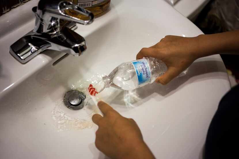  Jeremiah Loren, 12, rinses his toothbrush with bottled water at his home, amid the ongoing...