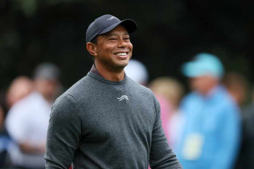 Tiger Woods reacts as he talks with fellow golfers as they walk down the second fairway...