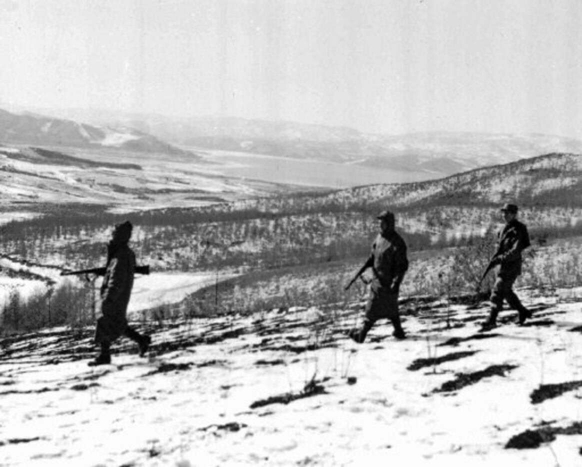 Marines patrol the icy hills near North Korea's Chosin Reservoir, which is visible in...