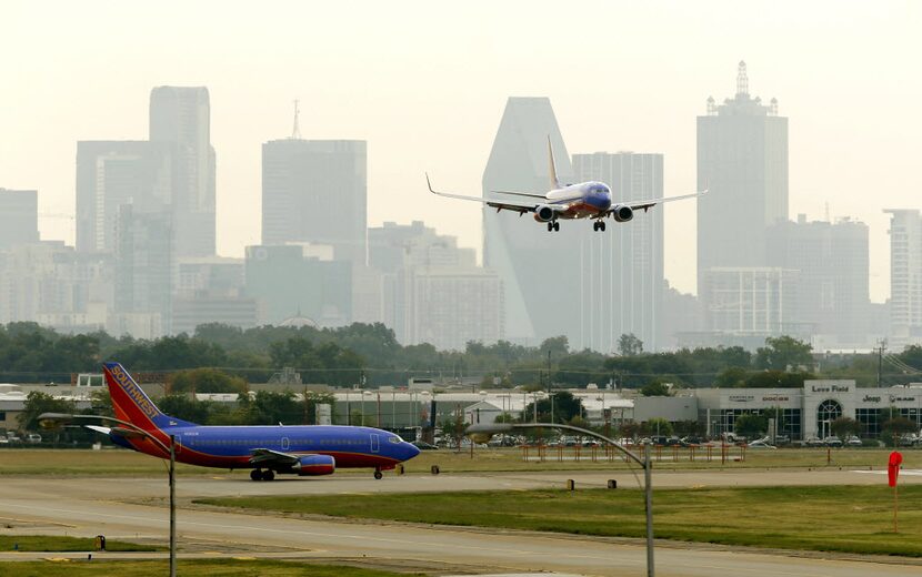 A Southwest Airlines plane comes in for a landing as another taxis the runway at Dallas Love...