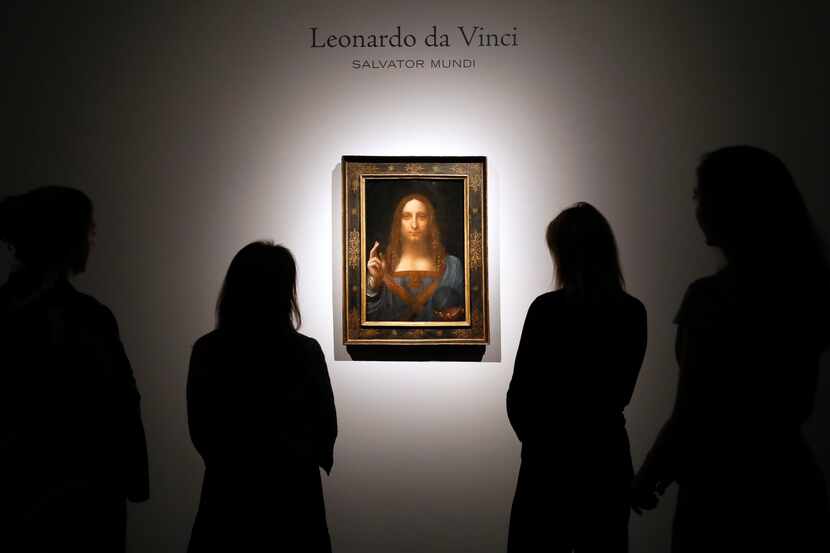 People gathered around Leonardo da Vinci's 'Salvator Mundi' at a Christie's auction room in...