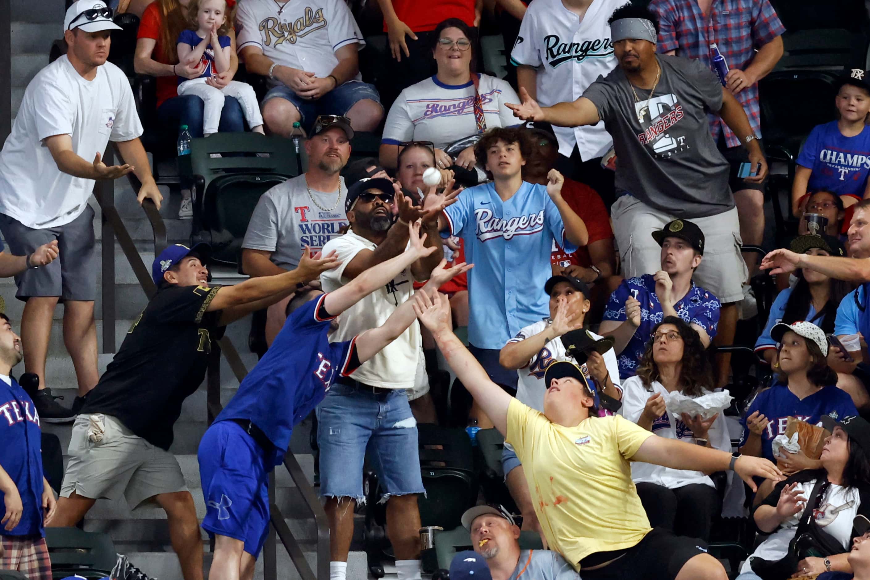 Fans reach out to catch a ball thrown by Texas Rangers right fielder Adolis Garcia during...