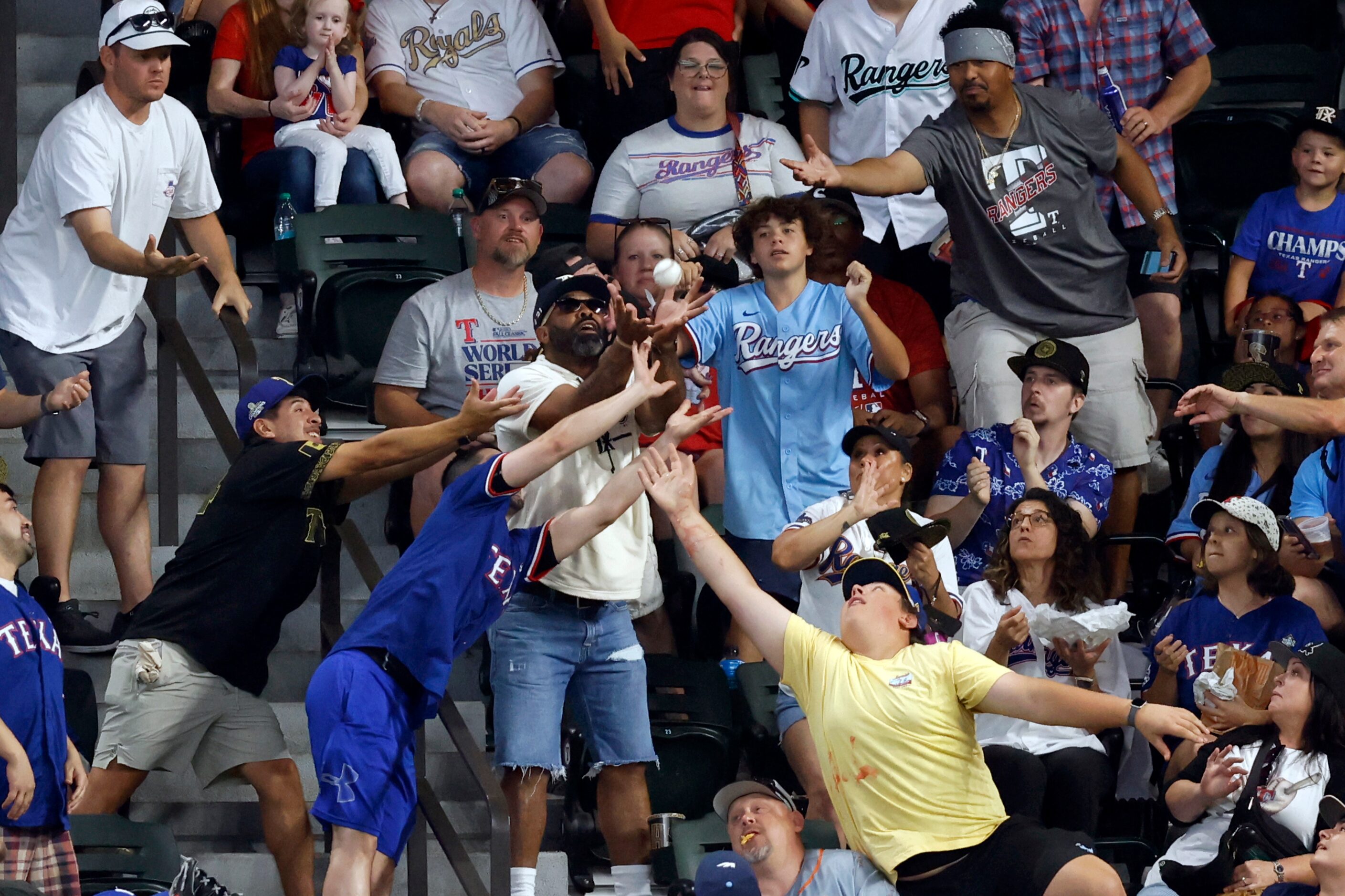 Fans reach out to catch a ball thrown by Texas Rangers right fielder Adolis Garcia during...