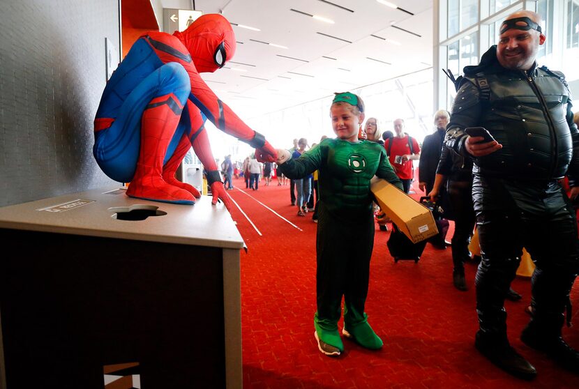 Lucas Hightower (Green Lantern), 8, of Bryan-College Station, Texas (center) receives a fist...