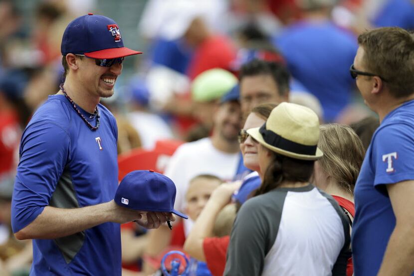 Texas Rangers' relief pitcher Tanner Scheppers, left, signs autographs for fans before a...