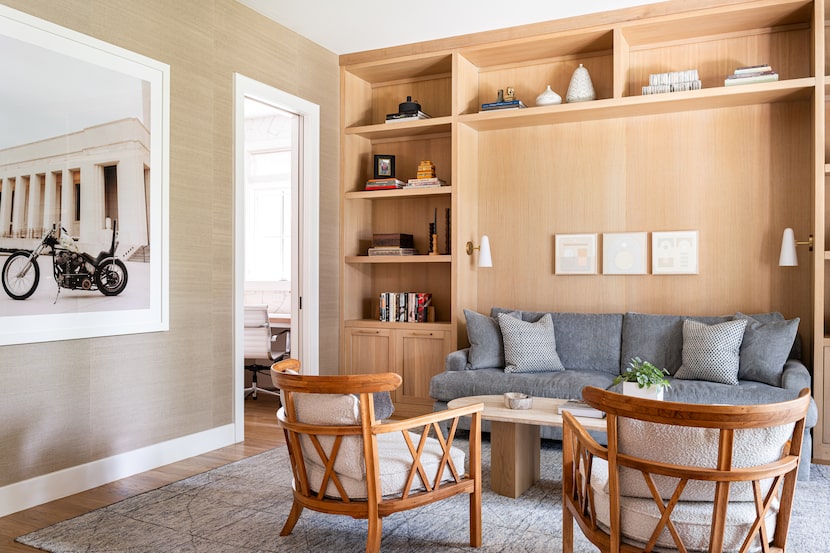 Library room with gray sofa, wooden chairs and a rug; motorcycle wall art is on the left side