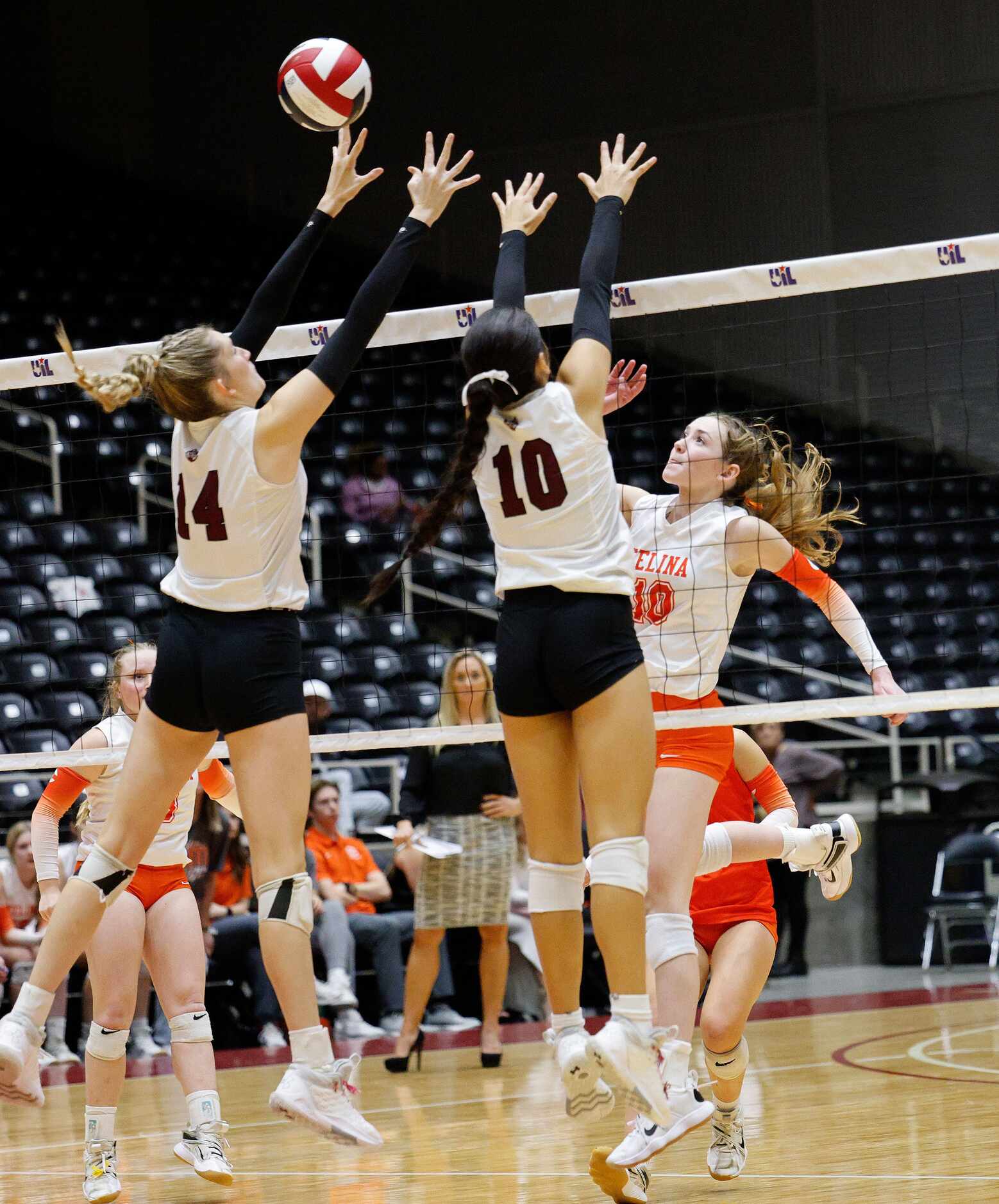 Celina's Ashley Woodrum (10) spikes the ball past Comal Davenport's Emily Williams (14) and...
